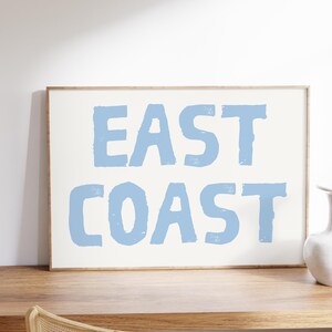 May include: A framed print with the text "EAST COAST" in light blue lettering on a white background.