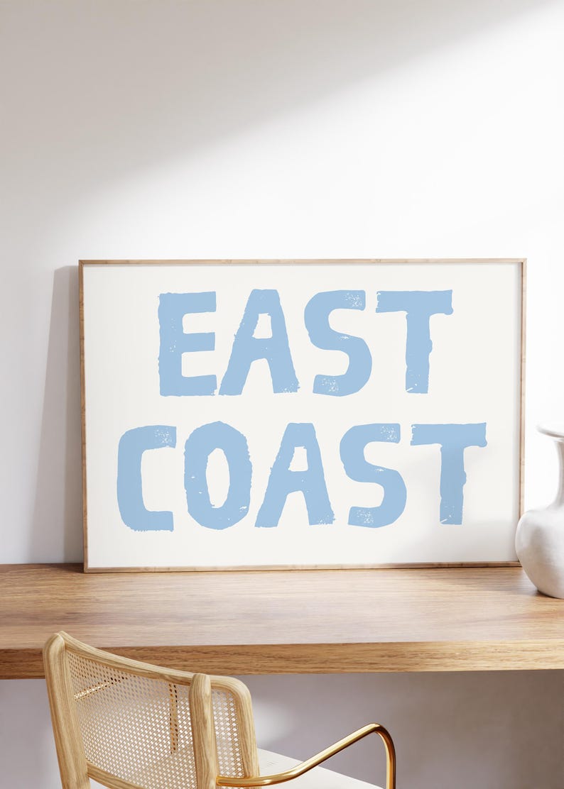 May include: A framed print with the text "EAST COAST" in light blue lettering on a white background.