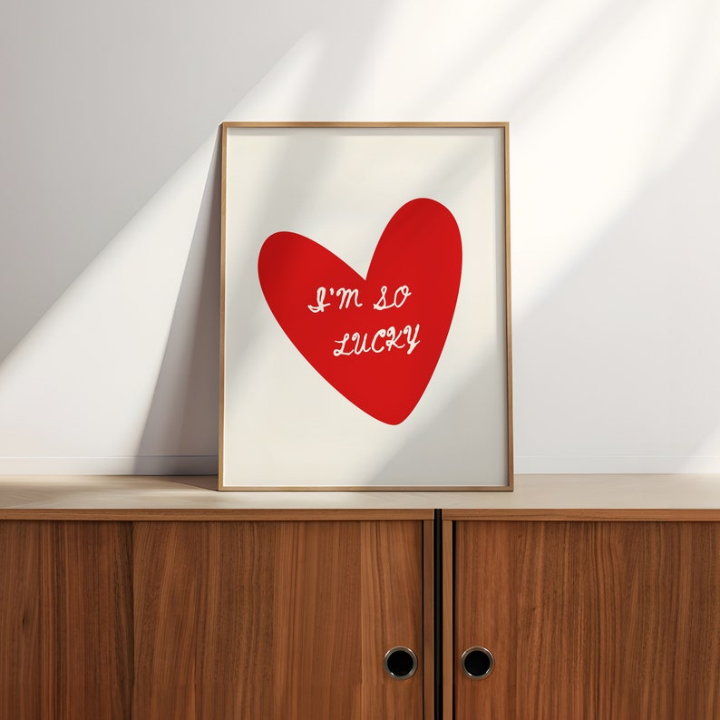 May include: A framed print with a red heart and the text "I'm so lucky" in white cursive writing.