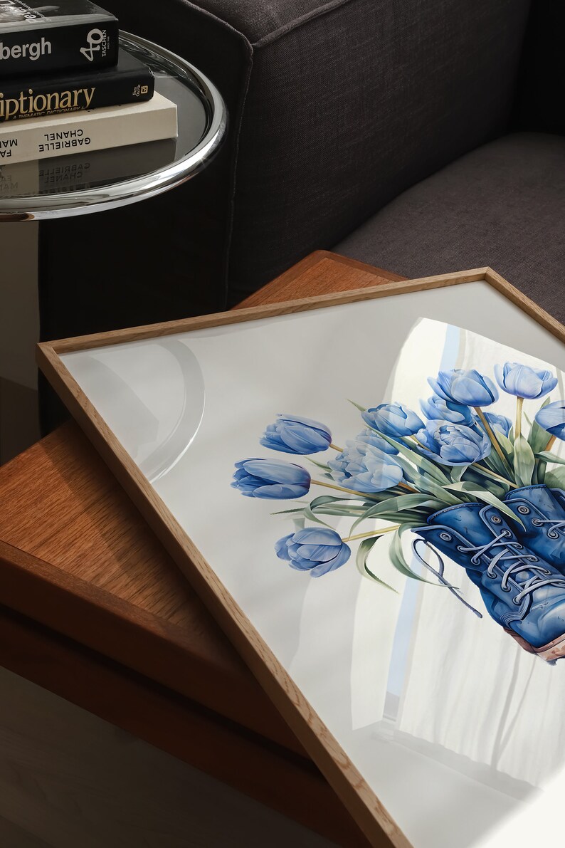 K&ouml;nnte beinhalten: Ein gerahmtes Aquarellbild von blauen Tulpen in einem Paar blauer Stiefel. Das Bild h&auml;ngt auf einem Holztisch.
