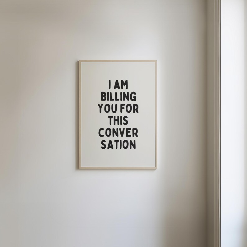 May include: A framed print with the text "I AM BILLING YOU FOR THIS CONVERSATION" in black lettering on a white background.