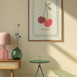 May include: A framed print with a green border and a white background. The print features a drawing of two red cherries with green stems and leaves. The text "ma ch&eacute;rie" is written below the cherries.