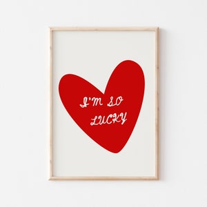 May include: A framed print with a red heart and the text "I'm so lucky" in white.