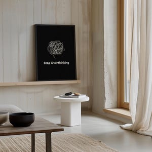 Pu&ograve; includere: Una stampa incorniciata in bianco e nero con un disegno a linea bianca di un fumetto con il testo "Stop Overthinking" su sfondo nero.