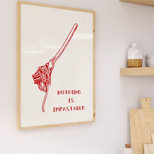 May include: A white framed print with a red illustration of a fork with spaghetti on it. The text "NOTHING IS IMPASTABLE" is written in red below the illustration.