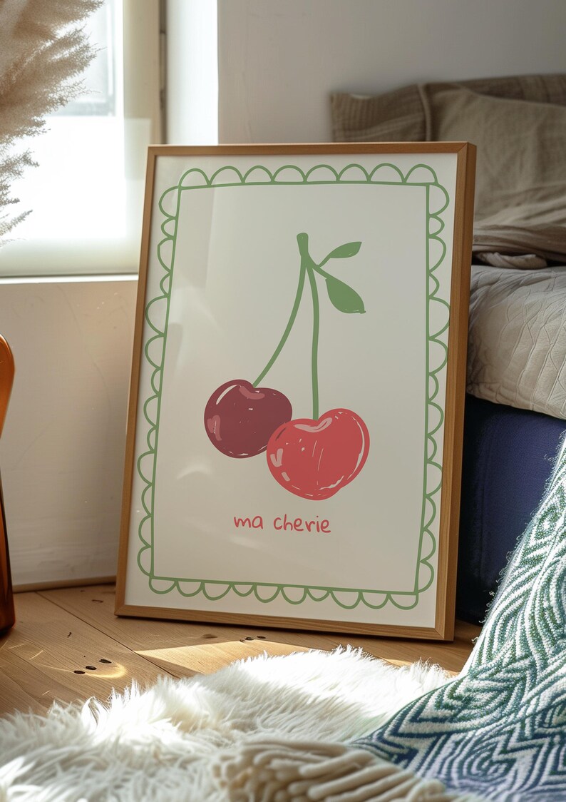 May include: A framed print with a green border and a white background. The print features a simple line drawing of two red cherries with green stems and leaves. The text "ma ch&eacute;rie" is written below the cherries.