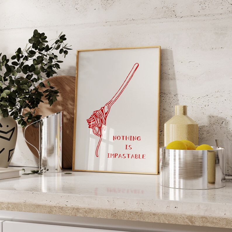 May include: A framed print with a red illustration of a fork with spaghetti on it. The text "Nothing is Impastable" is printed below the illustration.