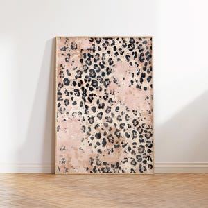 May include: A framed abstract print with a pink and black leopard print pattern. The print is in a wooden frame and is hanging on a white wall.