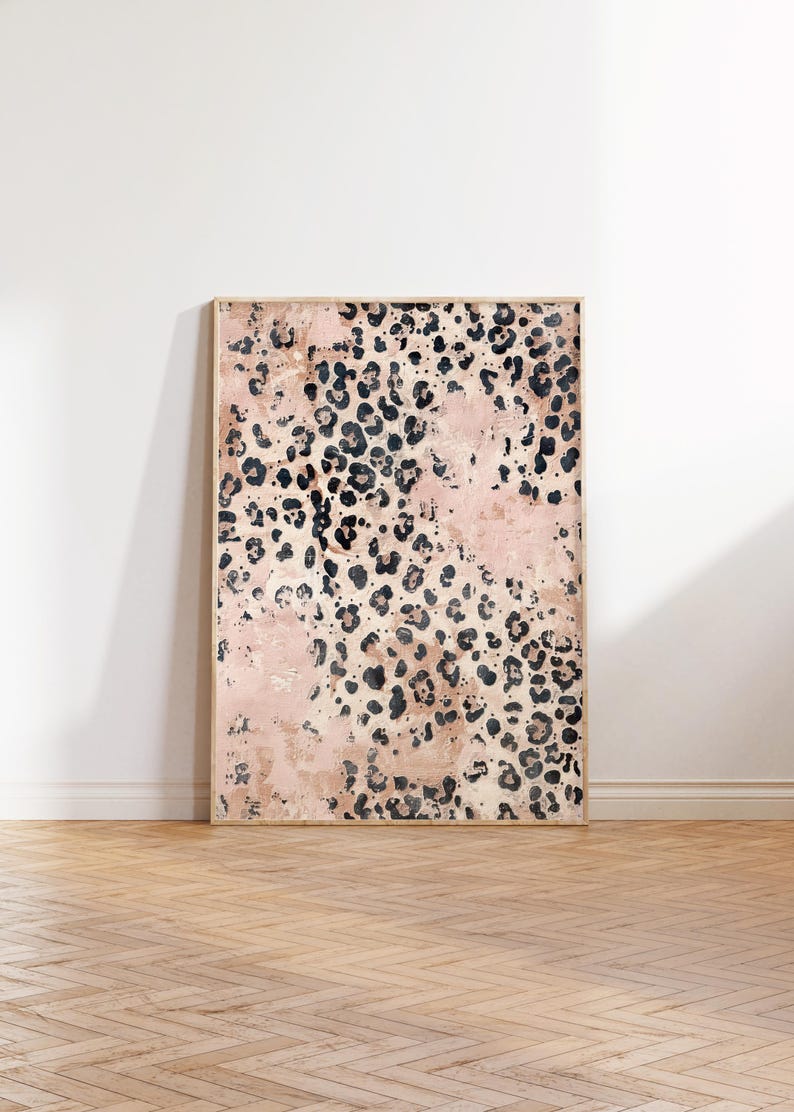 May include: A framed abstract print with a pink and black leopard print pattern. The print is in a wooden frame and is hanging on a white wall.