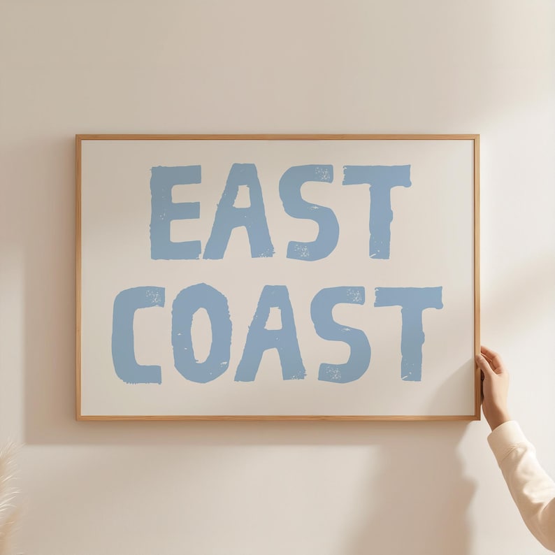 May include: A framed print with the text "EAST COAST" in a light blue color on a white background.