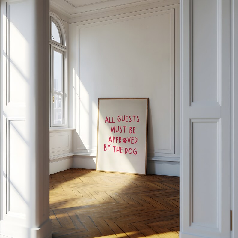 Puede incluir: Una impresi&oacute;n enmarcada con el texto "ALL GUESTS MUST BE APPRO*VED BY THE DOG" en letras rosas sobre un fondo blanco.