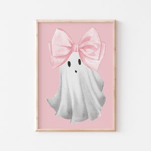 Pu&ograve; includere: Un fantasma bianco con un fiocco rosa sulla testa. Il fantasma ha un viso carino da cartone animato con due occhi neri e una piccola bocca. Lo sfondo &egrave; di colore rosa chiaro.