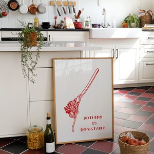 May include: A framed kitchen print with a red illustration of a fork twirling spaghetti. The text on the print reads "Nothing is Impassable".