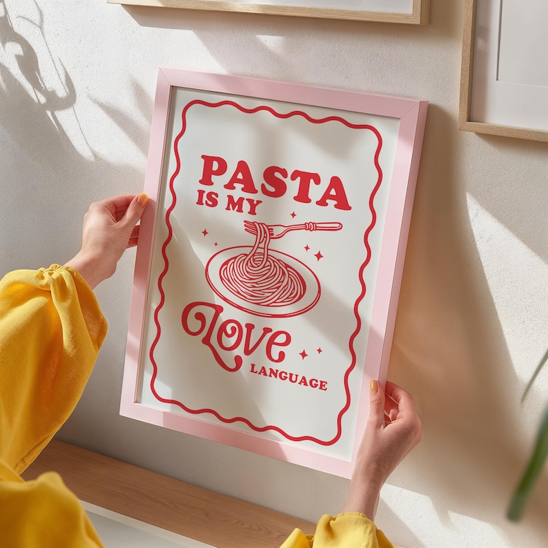 May include: A pink framed print with a white background and red text that says "PASTA IS MY LOVE LANGUAGE" with a drawing of a plate of spaghetti and a fork.