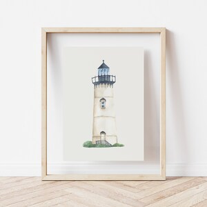 May include: A watercolor painting of a white lighthouse with a black roof and a black door. The lighthouse is set against a white background and is framed in a light wood frame.