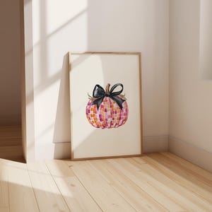 May include: A watercolor painting of a pink and orange checkered pumpkin with a black bow. The pumpkin is sitting on a white background.
