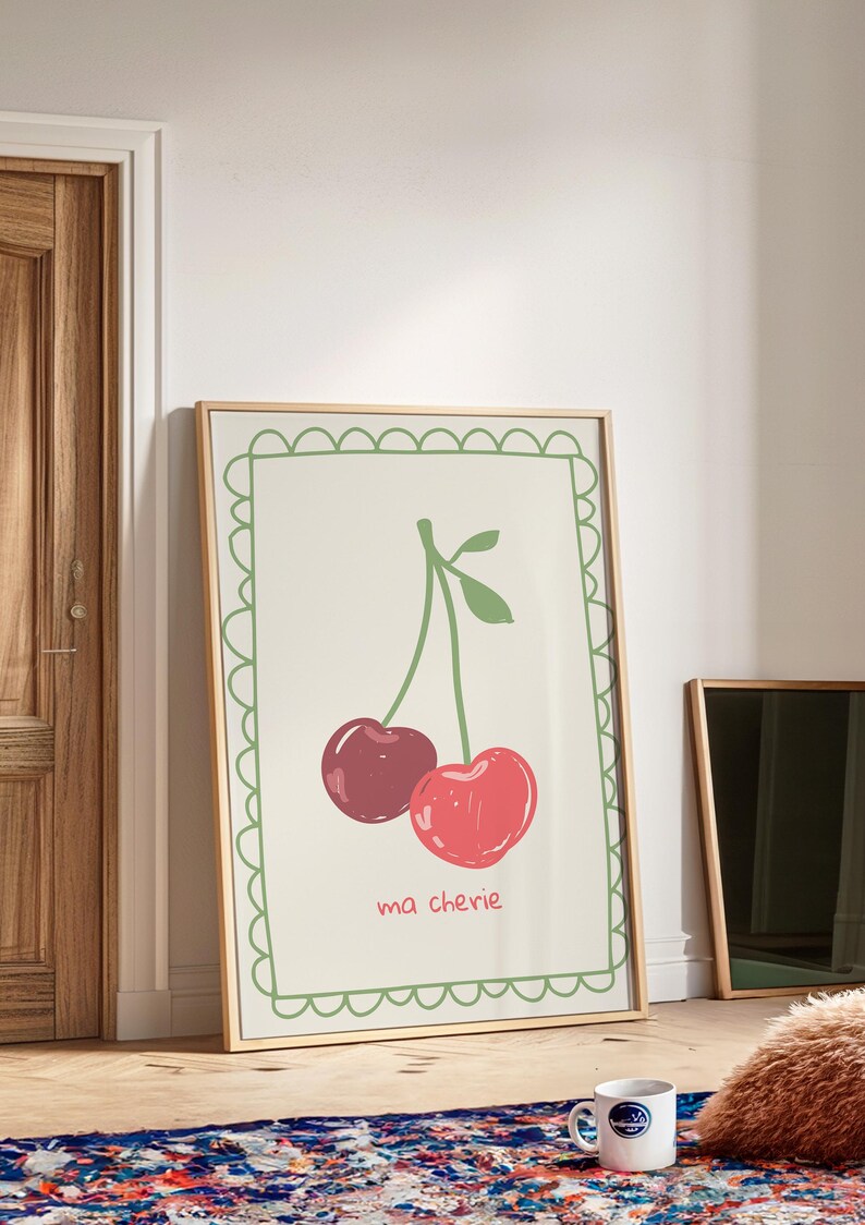 May include: A framed print with a green border featuring a drawing of two red cherries with a green stem and leaves. The text "ma ch&eacute;rie" is written below the cherries.
