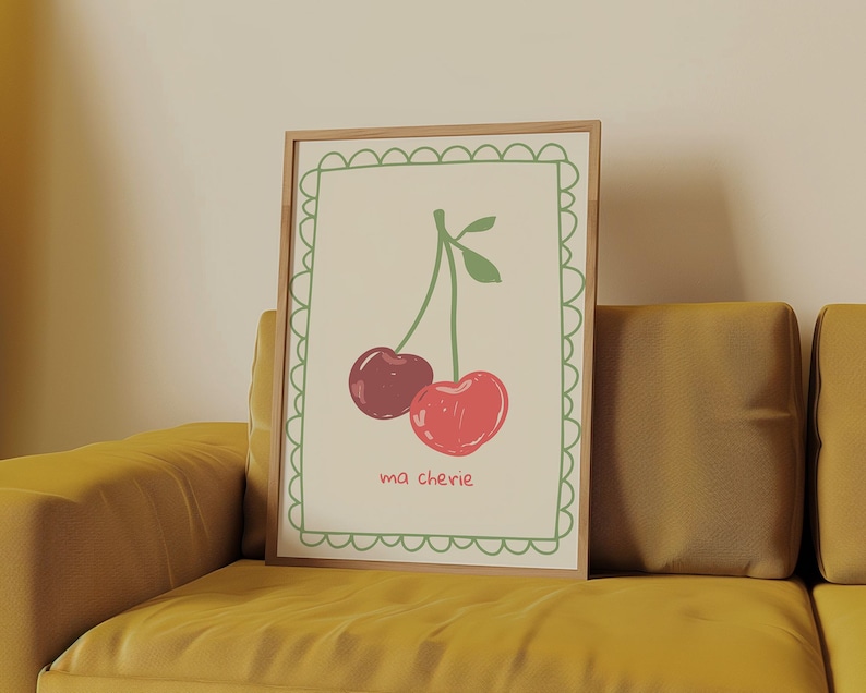 May include: A framed print with a white background and a green border. The print features a drawing of two red cherries on a stem with green leaves. The text "ma ch&eacute;rie" is written below the cherries.