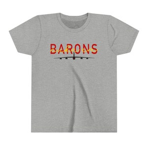 Könnte beinhalten: Ein heidefarbenes T-Shirt mit einer roten und gelben Grafik eines B-52-Bombers mit dem Text "BARONS" in gelber Schrift.