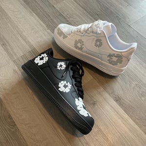 May include: A pair of white and black sneakers with a floral pattern. The sneakers are low-top and have a white sole.
