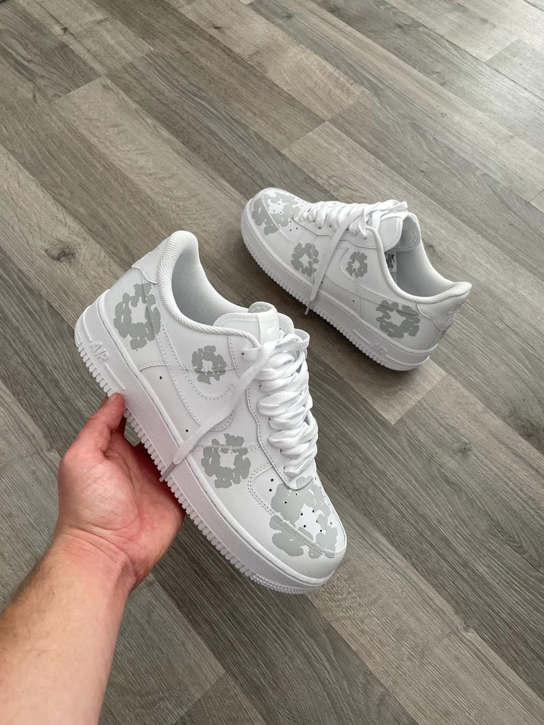 May include: White leather sneakers with a gray floral pattern. The sneakers have a white sole and laces.