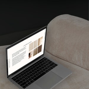May include: A silver laptop displaying a "COLOUR SCHEME" design concept, with text and color swatches. The laptop is open on a beige, textured surface, with a dark background. The keyboard is visible, and the screen is angled towards the viewer.