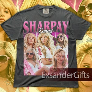 May include: Dark gray t-shirt featuring a pink graphic with the name "SHARPAY Evans" and a collage of images. The shirt has a vintage aesthetic, with a faded look. The text "ExsanderGifts" is at the bottom.