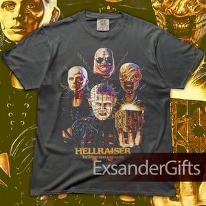 May include: Dark gray t-shirt featuring a graphic from the movie Hellraiser. The design includes several characters with grotesque features and the film's title. The text "He'll tear your soul apart" is also included.