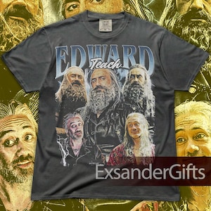 May include: Dark gray t-shirt featuring a graphic of several men with long hair and beards. The text "EDWARD Teach" is printed across the top in a blue and white font. The shirt has a vintage, distressed look.
