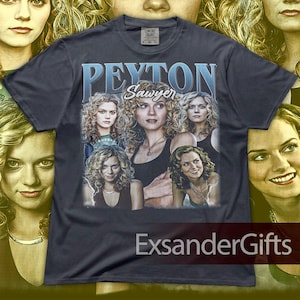 May include: Dark gray t-shirt featuring a collage of images of a woman, with the name "Peyton Sawyer" in blue text. The shirt has a vintage aesthetic, with the text "Comfort Colors" on the tag.