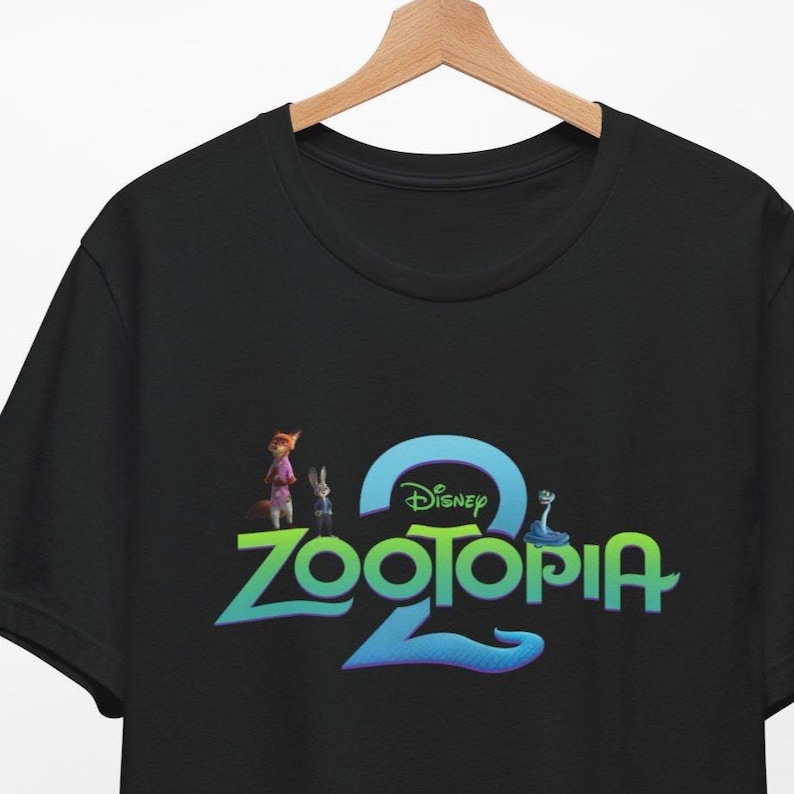 Puede incluir: Camiseta negra de cuello redondo con el logotipo de la pel&iacute;cula de Disney "Zootopia 2". El dise&ntilde;o incluye el t&iacute;tulo de la pel&iacute;cula en verde y azul, con el logotipo de Disney encima. La camiseta tambi&eacute;n presenta im&aacute;genes de los personajes.