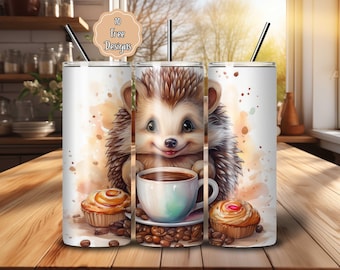 May include: A white tumbler with a whimsical design featuring a smiling hedgehog holding a coffee cup. The design includes coffee beans and pastries. The tumbler has a black straw and the text "10 Free Designs" on a decorative label.