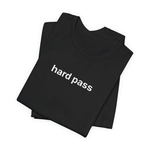 May include: Black t-shirt with the words "hard pass" printed in white. The t-shirt is folded and appears to be made of a soft material. The text is in a simple, sans-serif font.
