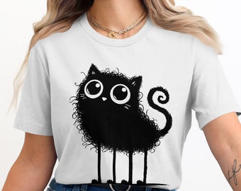 Puede incluir: Una camiseta blanca con un gato de dibujos animados negro con ojos grandes y una cola rizada.