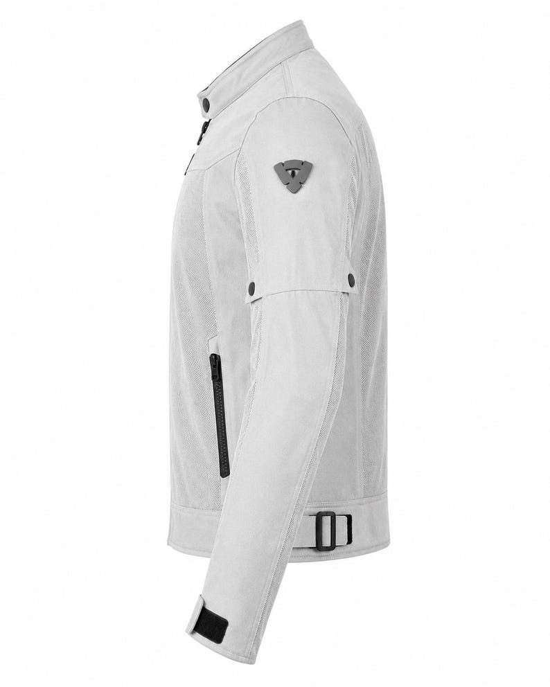 Pode incluir: Um blus&atilde;o de motociclista cinzento-claro com gola mandarim e bot&atilde;o de press&atilde;o, design em rede, emblema triangular cinzento-escuro na manga, bolsos pretos com fecho de correr e correias pretas ajust&aacute;veis com fivela na cintura e nos punhos.