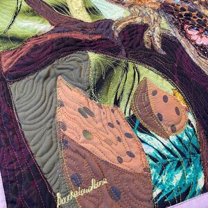 Close-up of the owl showing detailed fabric feathers, expressive eyes, floral accents, and layered textile textures.