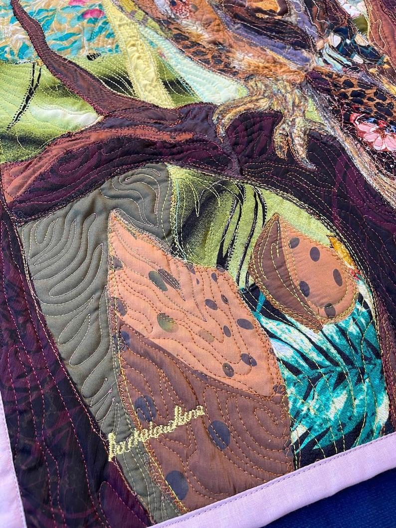 Close-up of the owl showing detailed fabric feathers, expressive eyes, floral accents, and layered textile textures.