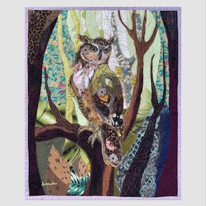 Close-up of the owl showing detailed fabric feathers, expressive eyes, floral accents, and layered textile textures.