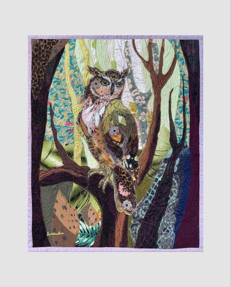 Close-up of the owl showing detailed fabric feathers, expressive eyes, floral accents, and layered textile textures.