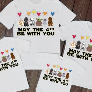 May include: Four white t-shirts with a Star Wars theme. The shirts feature a line of Star Wars characters with colorful balloons. The text on the shirts reads "May the 4th Be With You".