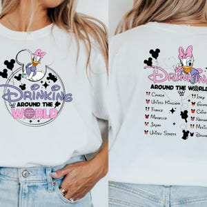May include: White t-shirt with a graphic of Daisy Duck and the text "Drinking Around the World." The design includes Mickey Mouse silhouettes and a world map with various countries. The back of the shirt lists countries.