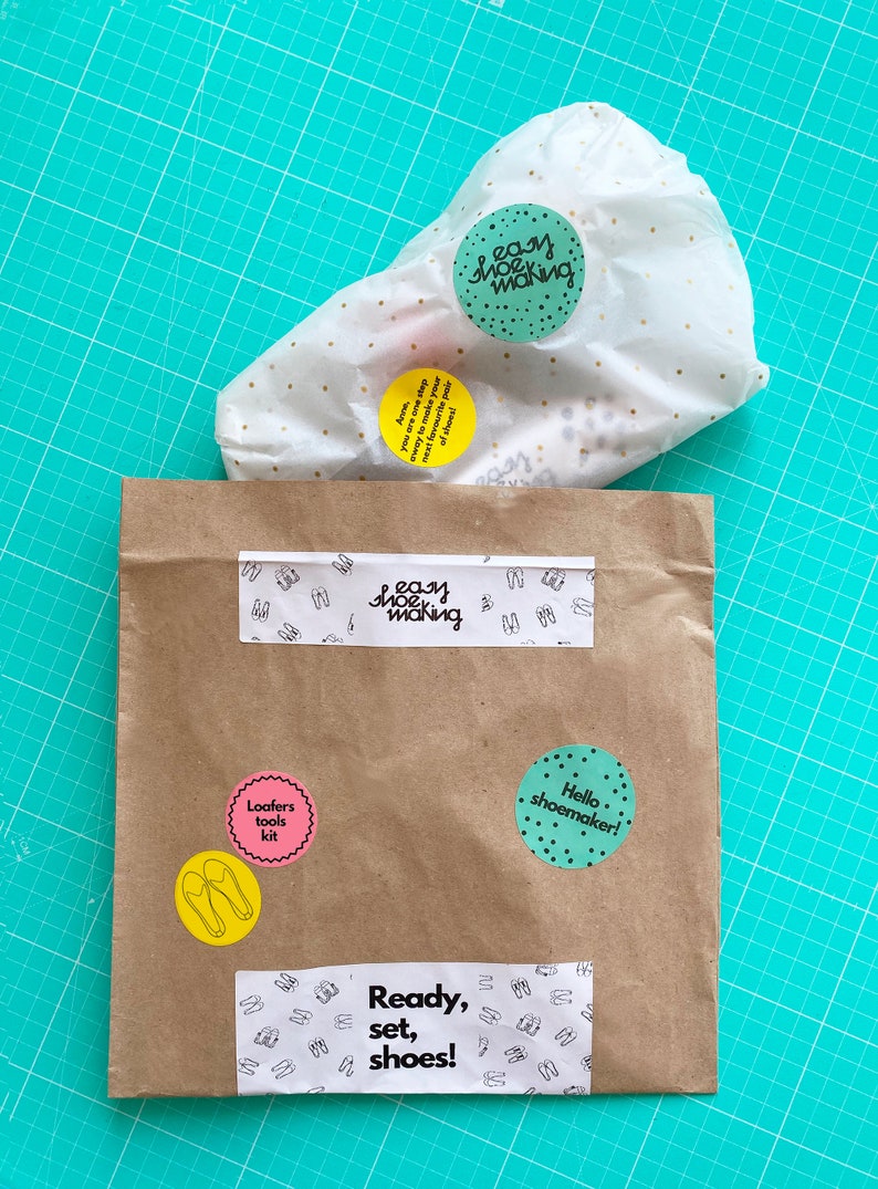 May include: A brown paper bag with various stickers on it. The stickers include the words "Easy Shoe Making", "Loafers Tools Kit", "Hello Shoemaker!" and "Ready, Set, Shoes!"