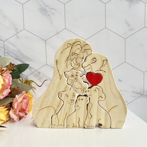 Puede incluir: Puzzle de madera de una familia de leones con un coraz&oacute;n rojo. El rompecabezas presenta a Simba, Nala y sus cachorros.