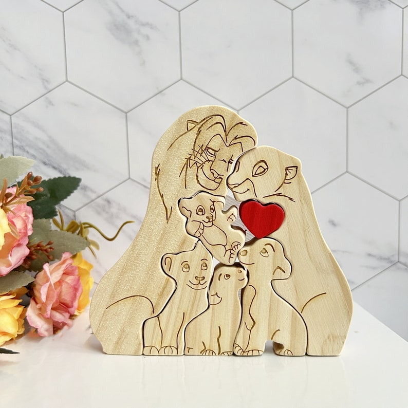 Puede incluir: Puzzle de madera de una familia de leones con un coraz&oacute;n rojo. El rompecabezas presenta a Simba, Nala y sus cachorros.
