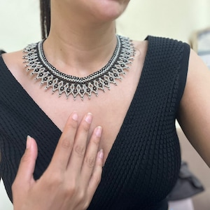 May include: A black and silver beaded choker necklace with a geometric design.