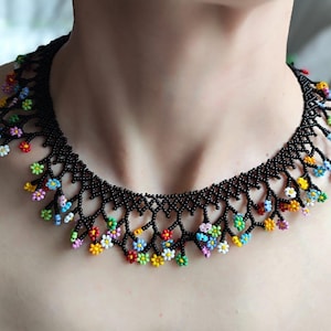 May include: A black beaded necklace with a delicate floral design. The flowers are made of colorful beads and are arranged in a cascading pattern.