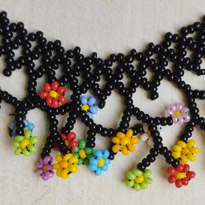 May include: A black beaded necklace with colorful flower-shaped beads. The necklace has a delicate, intricate design with dangling flower accents.
