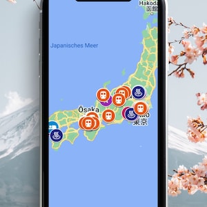 Puede incluir: Una captura de pantalla de un mapa de Japón en un teléfono inteligente. El mapa muestra varias ciudades y ubicaciones con iconos para estaciones de tren y aguas termales. El texto "Japanisches Meer" es visible en el mapa, que se traduce como "Mar de Japón" en español. El mapa está rodeado por un borde blanco y un fondo azul.
