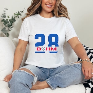 May include: White t-shirt with blue and red text that says "28 B♥HM".