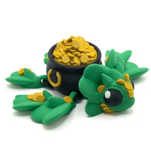 May include: A green, 3D printed dragon with gold accents is holding a black pot filled with gold coins. The dragon has a large, black eye and a small, black nose.